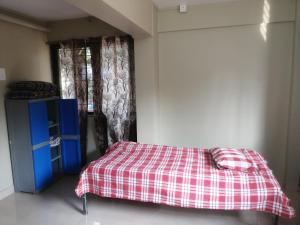 a bedroom with a bed with a checkered blanket at Samarth Homestay in Ratnagiri