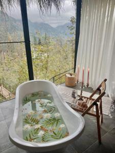 a bath tub sitting in front of a window with candles at Woodhide - Cottages near Batumi, Georgia in Zeda Ch'khutunet'i