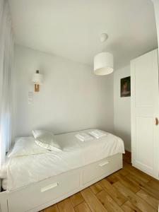 białe łóżko w pokoju z drewnianą podłogą w obiekcie Domek Aurory - Karkonosze w mieście Jeżów Sudecki