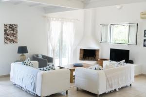 a living room with two white couches and a fireplace at Villa Eleonas in Strongylí