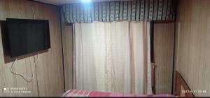 um quarto com uma televisão, uma cama e uma cortina em CASA ISLA MOTA em Valdivia