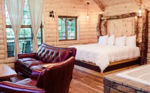 a bedroom with a bed and a couch and a tub at Cricket Hill Treehouse B by Amish Country Lodging in Millersburg