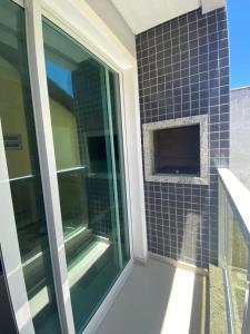La salle de bains est pourvue d'une fenêtre en verre sur un mur carrelé. dans l'établissement Apartamento à 100 metros da Praia Dos Ingleses, à Florianópolis