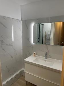 La salle de bains blanche est pourvue d'un lavabo et d'un miroir. dans l'établissement magnifique Duplex avec 2 chambres et parking gratuit, à Grenoble