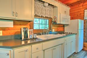 a kitchen with white cabinets and a sink and a refrigerator at Grapevine Cabin by Amish Country Lodging in Millersburg