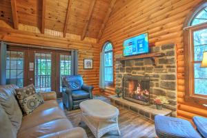 a living room with a fireplace and a tv at Grapevine Cabin by Amish Country Lodging in Millersburg