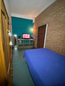um quarto com uma cama azul e uma televisão em Cerro Chico em Villa Cura Brochero