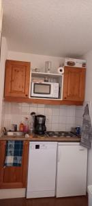 eine Küche mit weißen Geräten und Holzschränken in der Unterkunft 2 pièces sur les hauteurs de Saint-François-Longchamp in Saint-François-Longchamp