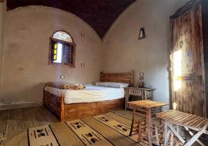 a bedroom with a bed and a table and a window at Best One - بيست ون in Siwa
