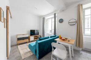 a living room with a blue couch and a table at Les studios Jean Bringer - Carcassonne centre-ville in Carcassonne