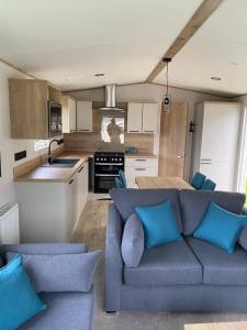 a living room with a blue couch and a kitchen at Coastal caravan with superb view in Bembridge