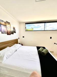 1 dormitorio con cama blanca y ventana en LOFT IGUASSU FALLS *GARAGEM* en Foz do Iguaçu