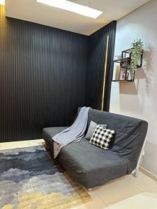 ein Sofa im Wohnzimmer mit schwarzer Wand in der Unterkunft Infinity Pool Netflix 100Mbps apartment in Shah Alam
