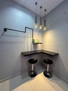 einen schwarzen Schreibtisch mit zwei Hockern in einem Zimmer in der Unterkunft Infinity Pool Netflix 100Mbps apartment in Shah Alam