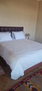 un letto con lenzuola e cuscini bianchi in una camera da letto di VILLA ROSERAIE a Marrakech