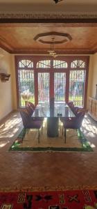 a dining room with a table and chairs and windows at VILLA ROSERAIE in Marrakech