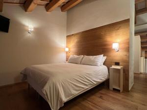 1 dormitorio con cama blanca y cabecero de madera en Mezzo Ciel, en Crespano del Grappa