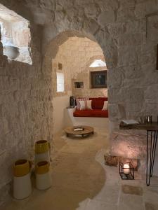 een woonkamer met een rode bank in een stenen muur bij TRULLI TERRA DI MEZZO in Cisternino