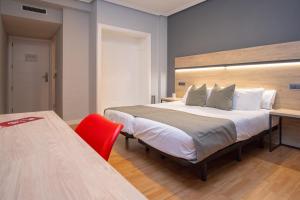 a bedroom with a large bed and a red chair at AZ Hotel El Príncipe in Zaragoza