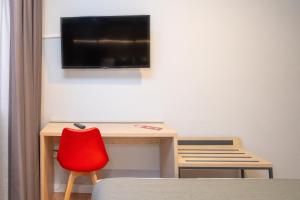 a desk with a red chair and a tv on a wall at AZ Hotel El Príncipe in Zaragoza