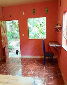 Cette chambre est dotée de murs rouges et d'une chaise bleue. dans l'établissement Quarto na floresta com saída no igarapé - Espaço Caminho das pedras, à Alter do Chão