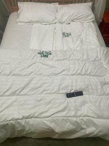Una cama blanca con mando a distancia. en The First Royal Tour Lodge en Dodoma