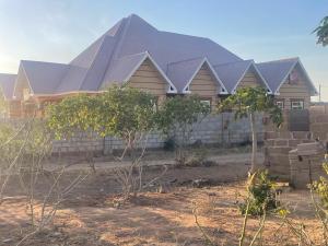 una casa con un techo con árboles delante de ella en The First Royal Tour Lodge en Dodoma