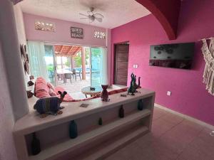 ein Wohnzimmer mit rosa Wänden und einem Tisch mit Figuren in der Unterkunft Casa Mana: Beachfront Home w/pool on Playa Blanca in Zihuatanejo