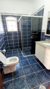 uma casa de banho em azulejos azuis com um WC e um lavatório em Pousada Genesis Guaruja no Guarujá