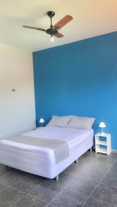Cama en habitación con pared azul en Pousada Genesis Guaruja, en Guarujá