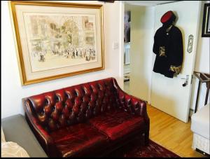 un sofá de cuero rojo en una sala de estar con una foto en Quality and very good value private accommodation in London close to Notting Hill Zone 2, en Londres