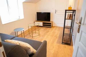Una sala de estar con un sofá y un televisor. en Gîte Les Camélias 2 chambres, 2 salles de bains, en Villers-Cotterêts