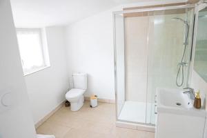 Un baño blanco con ducha y WC. en Gîte Les Camélias 2 chambres, 2 salles de bains, en Villers-Cotterêts 1 foto más