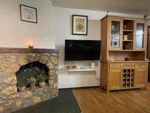 a living room with a tv and a stone fireplace at Modern Täsch Apartment with Free Parking in Täsch