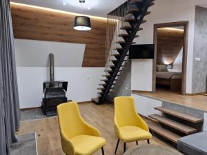 a living room with yellow chairs and a staircase at Bajkoviti bungalov in Pale