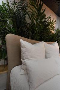 Cette chambre comprend un lit avec des oreillers et des plantes blancs. dans l'établissement Le Nature - Sauna - Balnéo - Sparoom Sarreguemines, à Sarreguemines