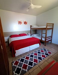a bedroom with a bed with a red blanket and a rug at POUSADA EVELINA in Foz do Iguaçu