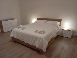 una camera da letto con un grande letto bianco con due comodini di La casetta - casa vacanze a Bisceglie