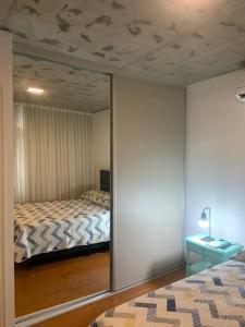 Dormitorio con espejo y reflejo de cama en Golf en Rosario