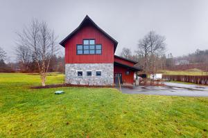 une grange rouge avec un toit noir dans un champ dans l'établissement Mountain View, à Stowe