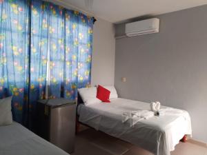 Habitación con 2 camas y ventana con cortina en Hotel María Inés en Veracruz
