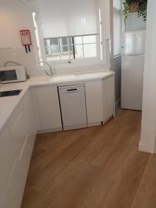 cocina con armarios blancos y suelo de madera en Apartamento Centro Nerja proxi playas, en Nerja