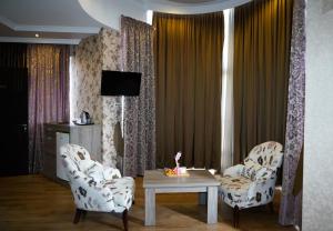 a living room with two chairs and a table and a tv at Hotel Monopoli Kutaisi in Kutaisi