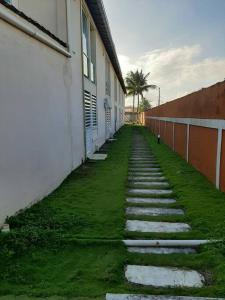 un chemin en pierre à côté d'un bâtiment avec un palmier dans l'établissement Apartamento frente ao mar na praia do guaibim., à Guaibim