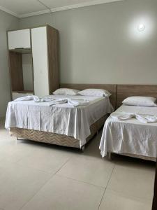 two twin beds in a room with a mirror at Apartamento frente ao mar na praia do guaibim. in Guaibim