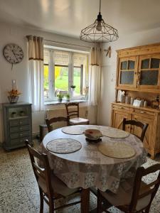 a dining room with a table and chairs and a clock at Ancienne Fermette le Charlemont Givet Foisches in Foisches