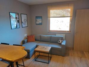 a living room with a blue couch and a table at Apartman 519 - Aparthotel Vučko in Jahorina