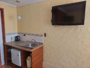 uma cozinha com um lavatório e uma televisão de ecrã plano na parede em Hostal El Gallego em El Quisco