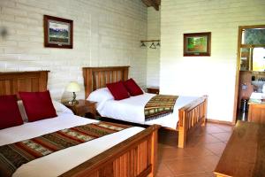 a hotel room with two beds and a table at Hosteria Cananvalle in Ibarra