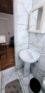 uma casa de banho branca com um lavatório e um espelho em KITNET S3 em TORRES-RS - Ar-condicionado, cama casal box, bicama, frigobar, micro-ondas, televisão telinha 32' - Anfitriã Superhost no BnB em Torres